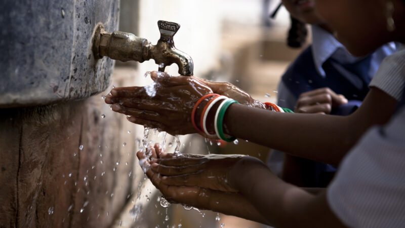Indian children washing their hands at an outside tap