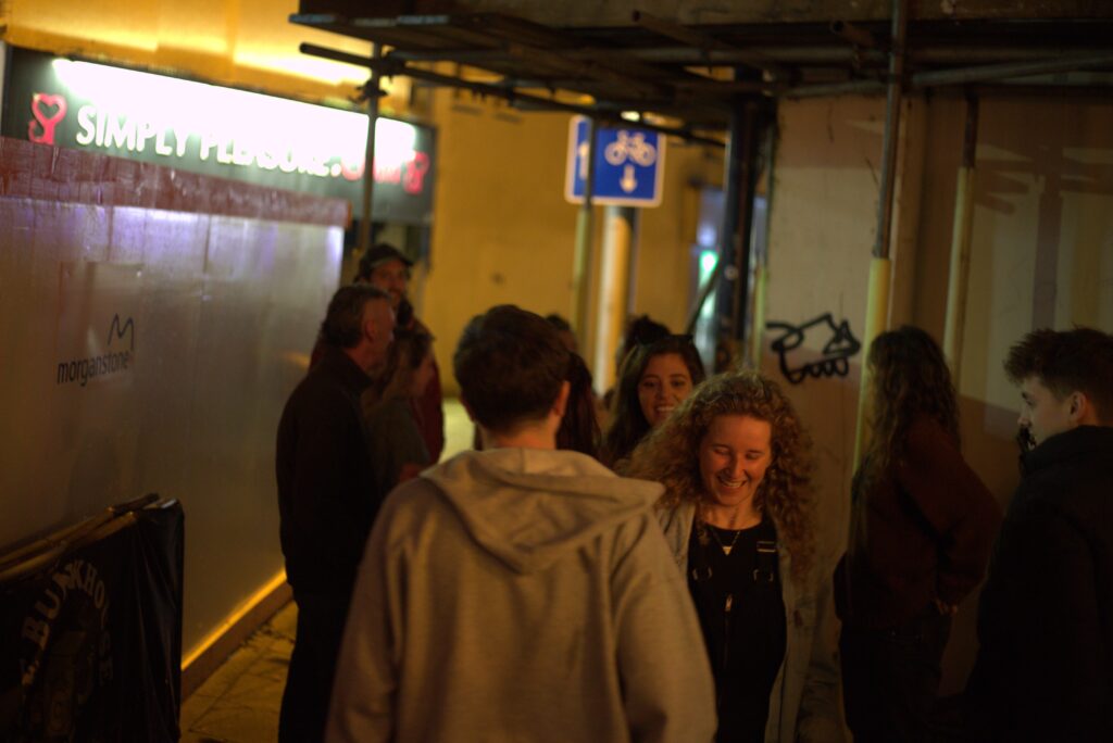 A group of people smiling and talking outside the venue.